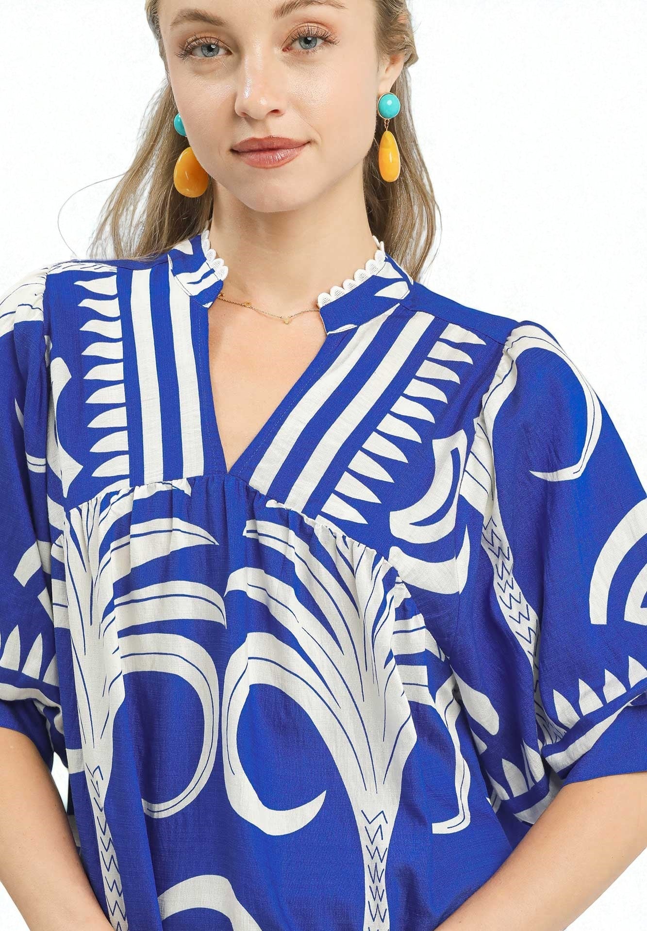 Woman wearing a blue and white patterned dress with earrings on a white background