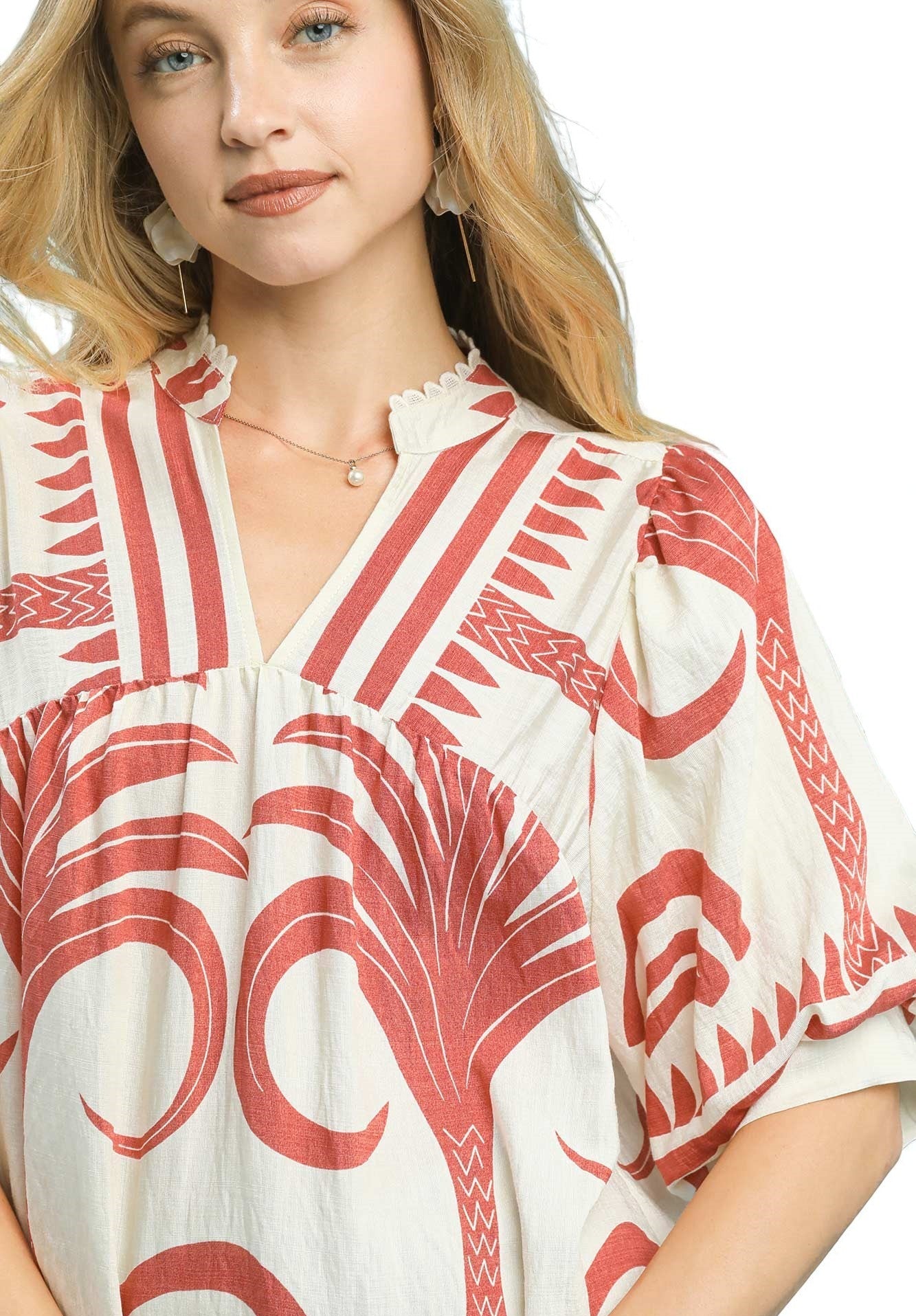 Woman wearing a red and white patterned blouse on a plain background
