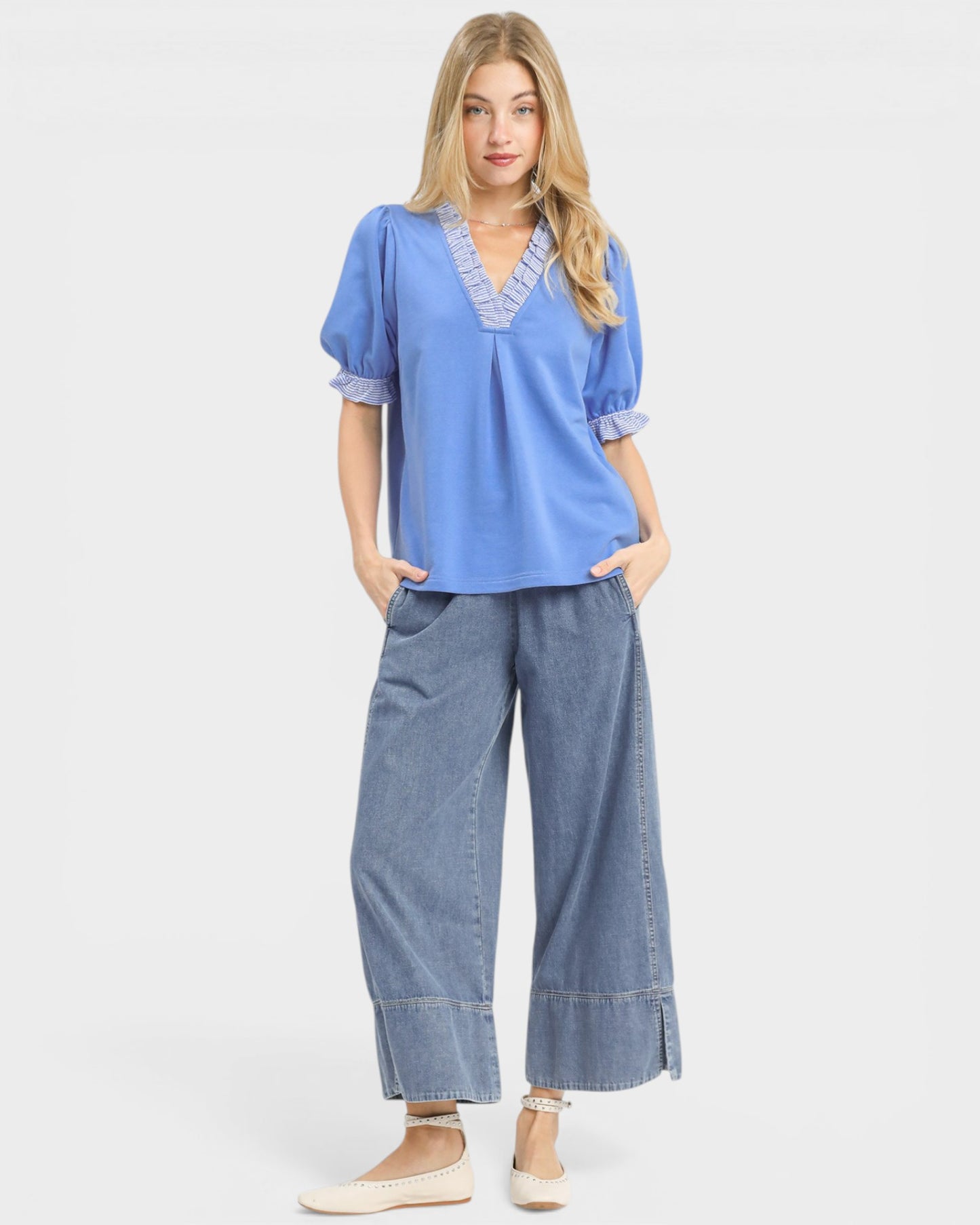 Woman wearing a blue top and denim pants on a white background