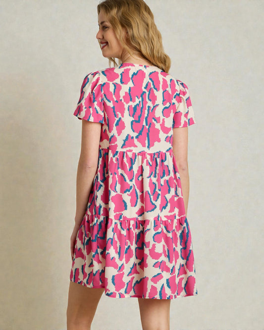 Woman wearing a pink and blue patterned dress against a plain background