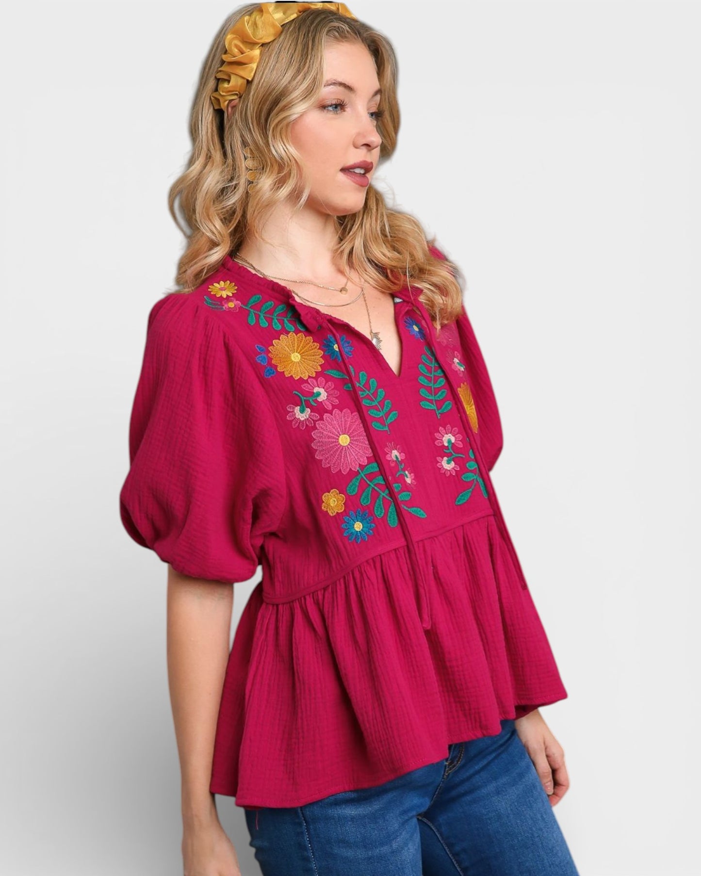 Woman wearing a pink blouse with floral embroidery on a white background