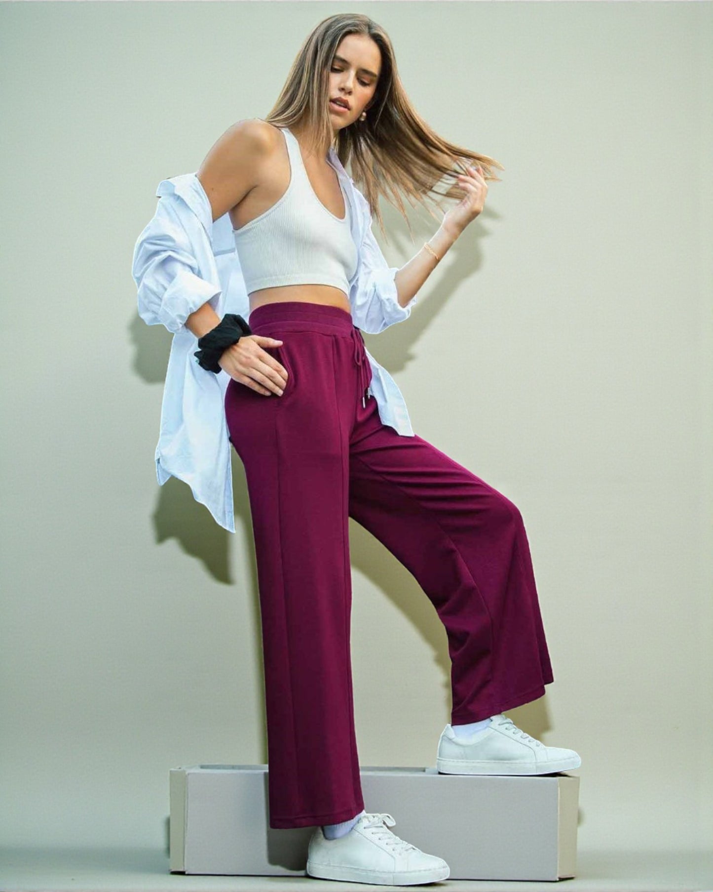 Woman in athletic wear posing on a box against a plain background