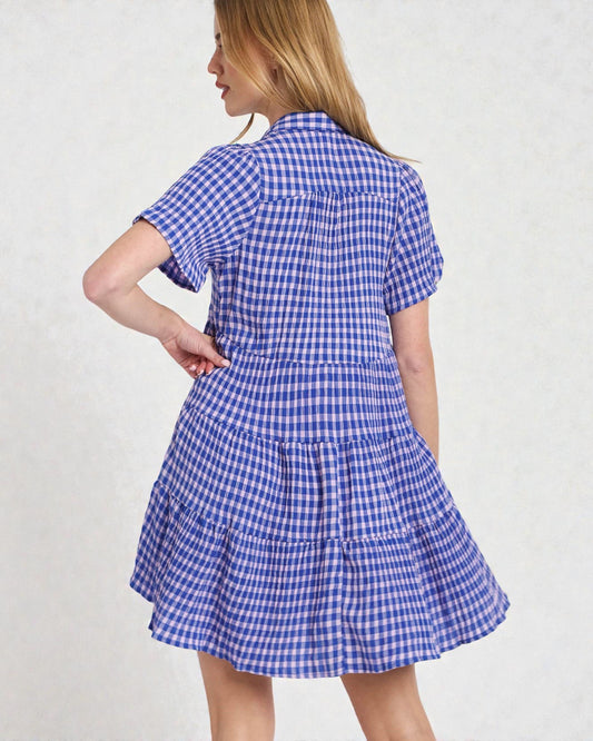 Woman wearing a blue and white checkered dress on a plain background