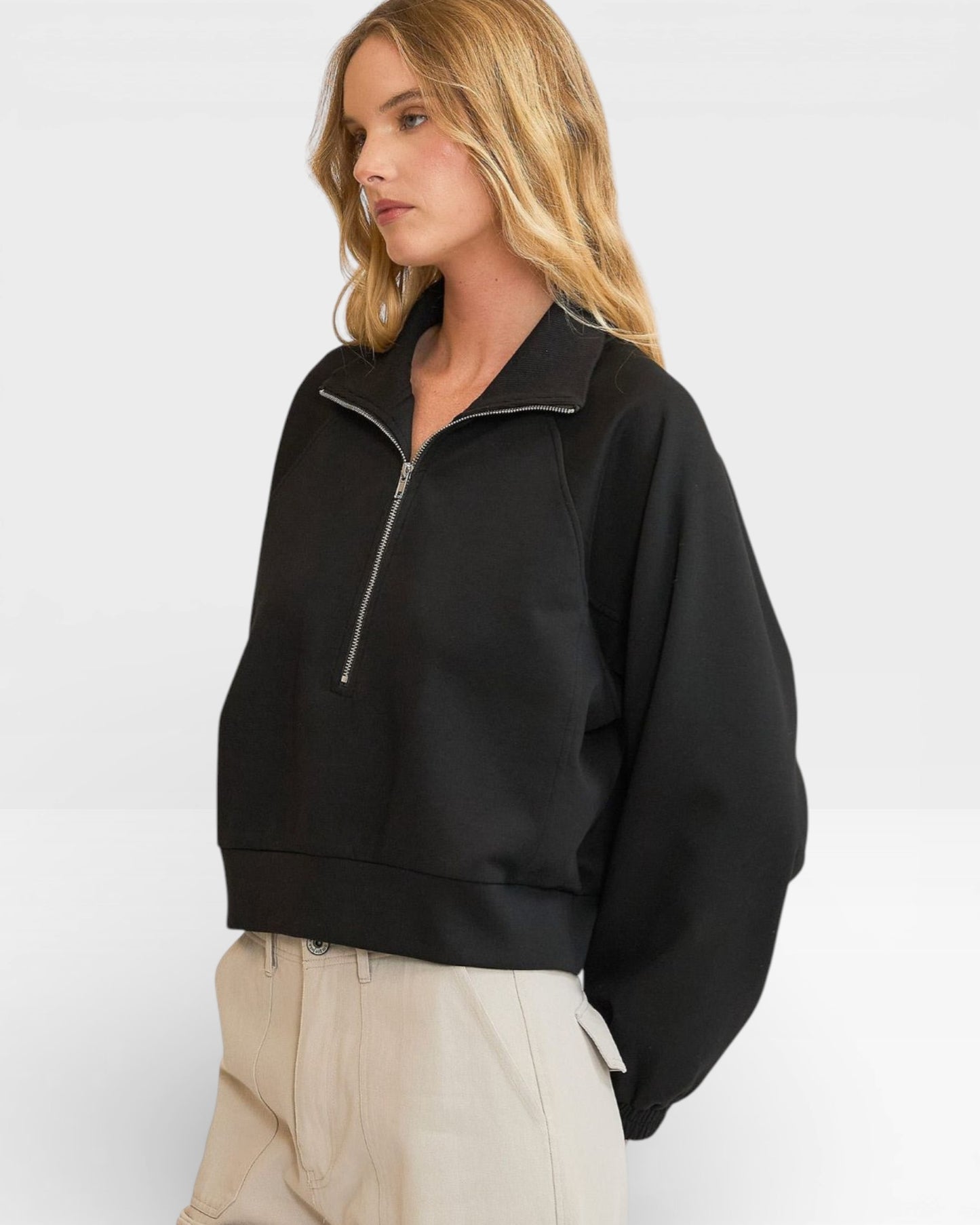 Woman wearing a black half-zip sweatshirt on a white background