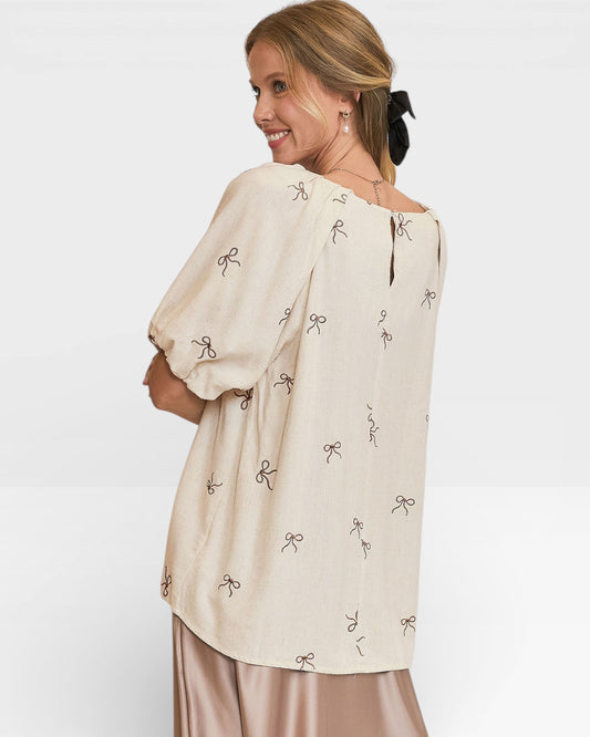 Woman wearing a beige blouse with bow patterns on a white background