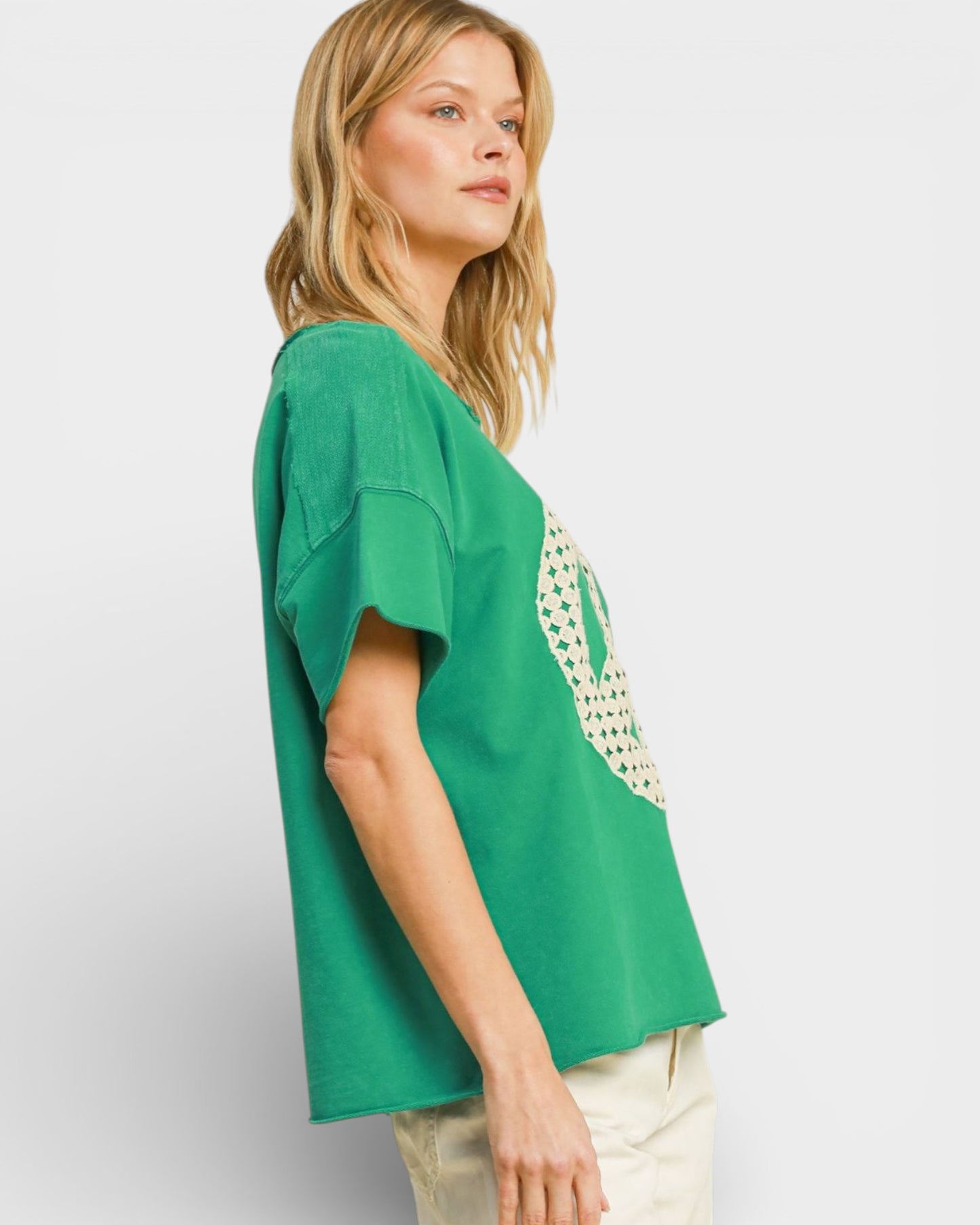 Woman wearing a green top with a floral pattern on a plain background