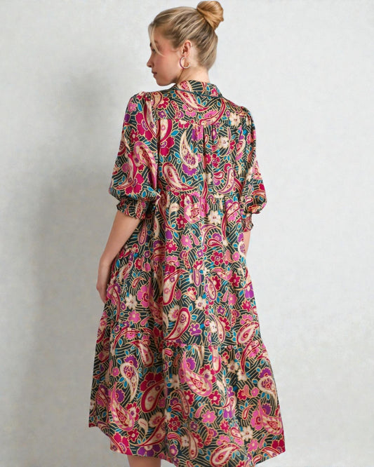 Woman wearing a colorful patterned dress against a plain background