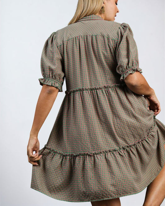 Woman wearing a green checkered dress against a plain background
