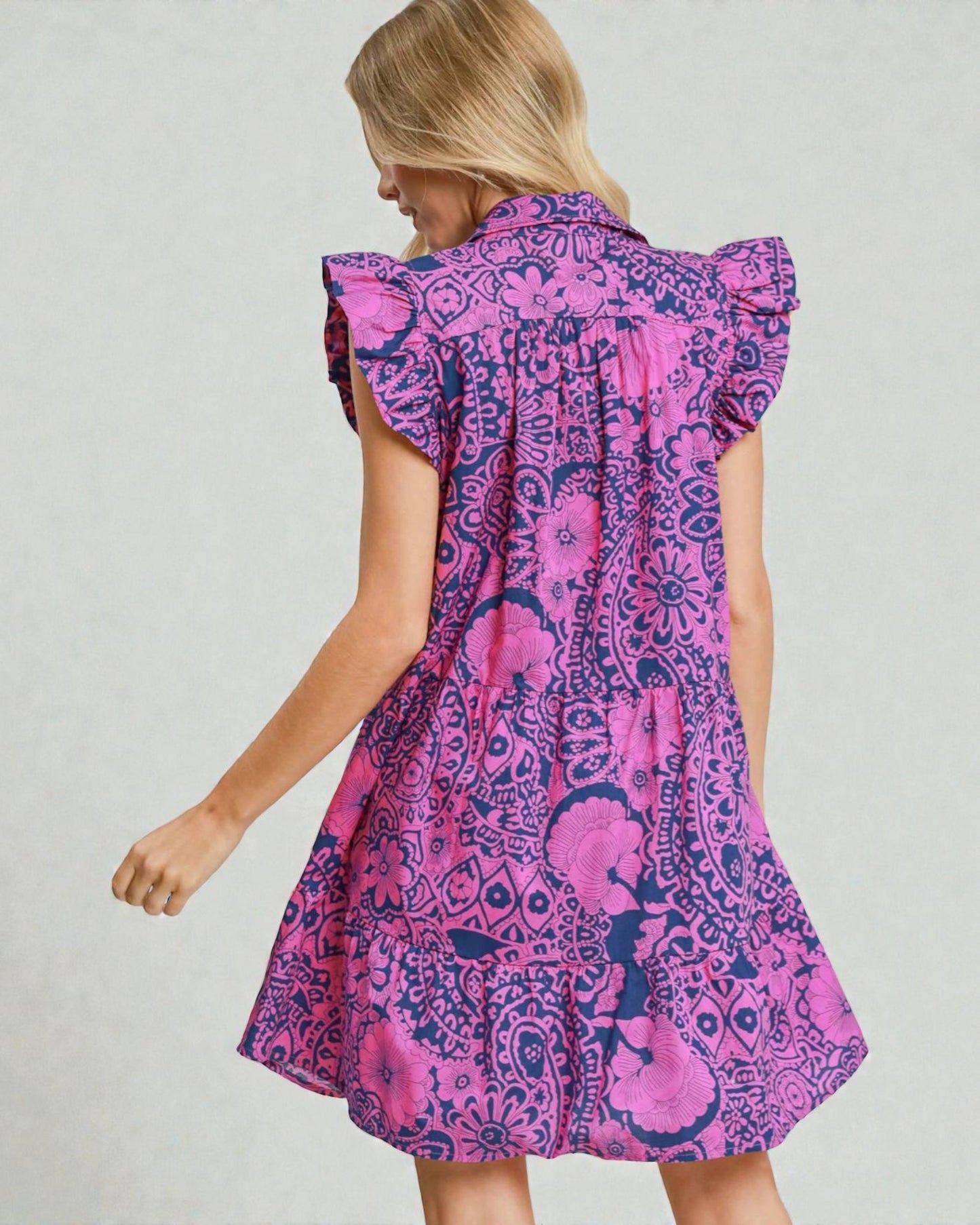 Woman wearing a pink and purple patterned dress on a plain background