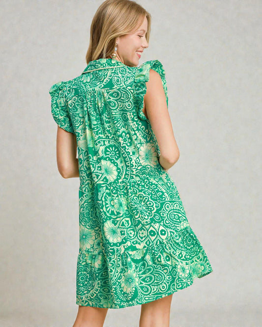 Woman wearing a green patterned dress against a plain background