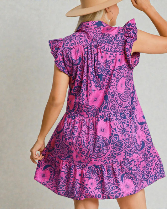 Woman wearing a pink and purple patterned dress against a neutral background