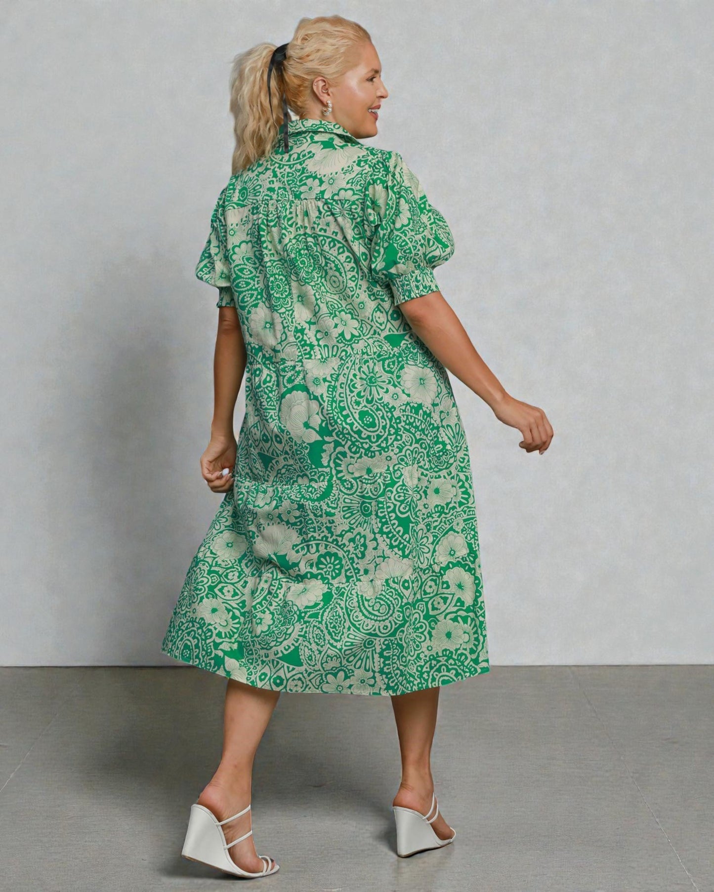 Woman wearing a green patterned dress against a plain background