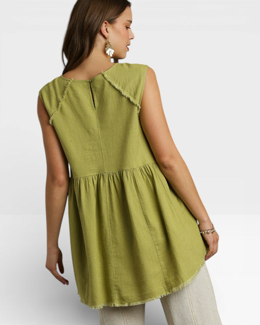Woman wearing a green sleeveless top with ruffled neckline on a white background