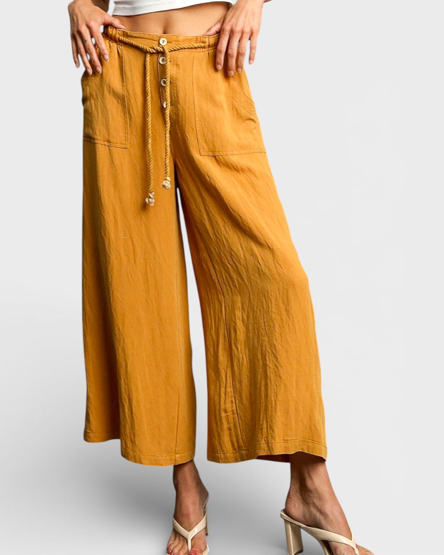 Mustard yellow wide-leg pants with button details on a white background
