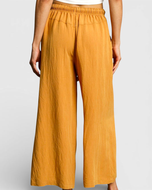 Mustard yellow wide-leg pants worn by a person on a light gray background