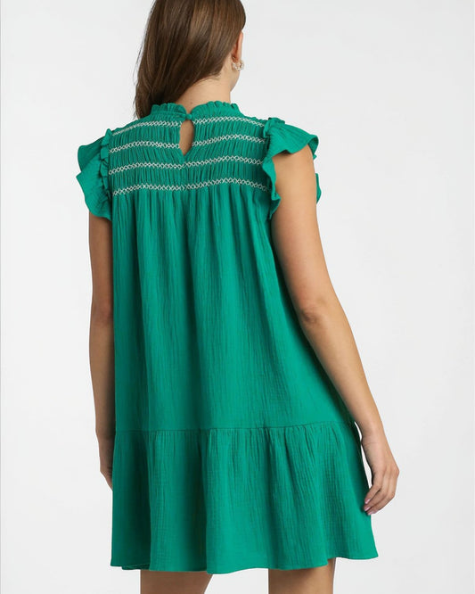 Green dress with ruffled sleeves and trim on a white background
