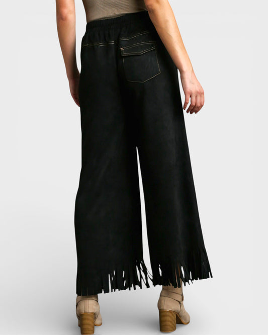 Black fringed pants worn by a person on a white background