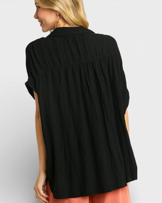 Woman wearing a black blouse with a plain background