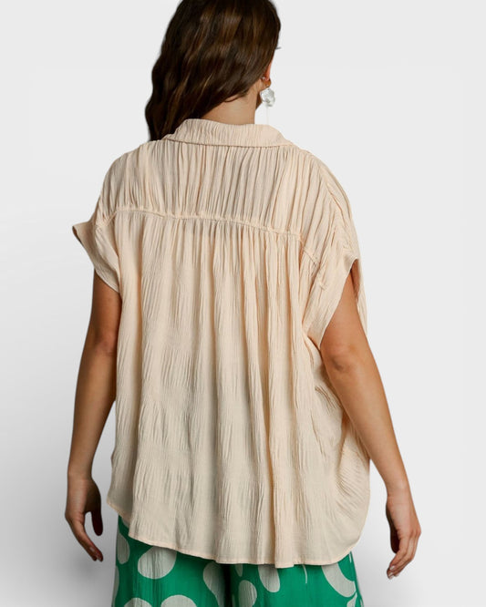 Woman wearing a beige sleeveless top with a plain background