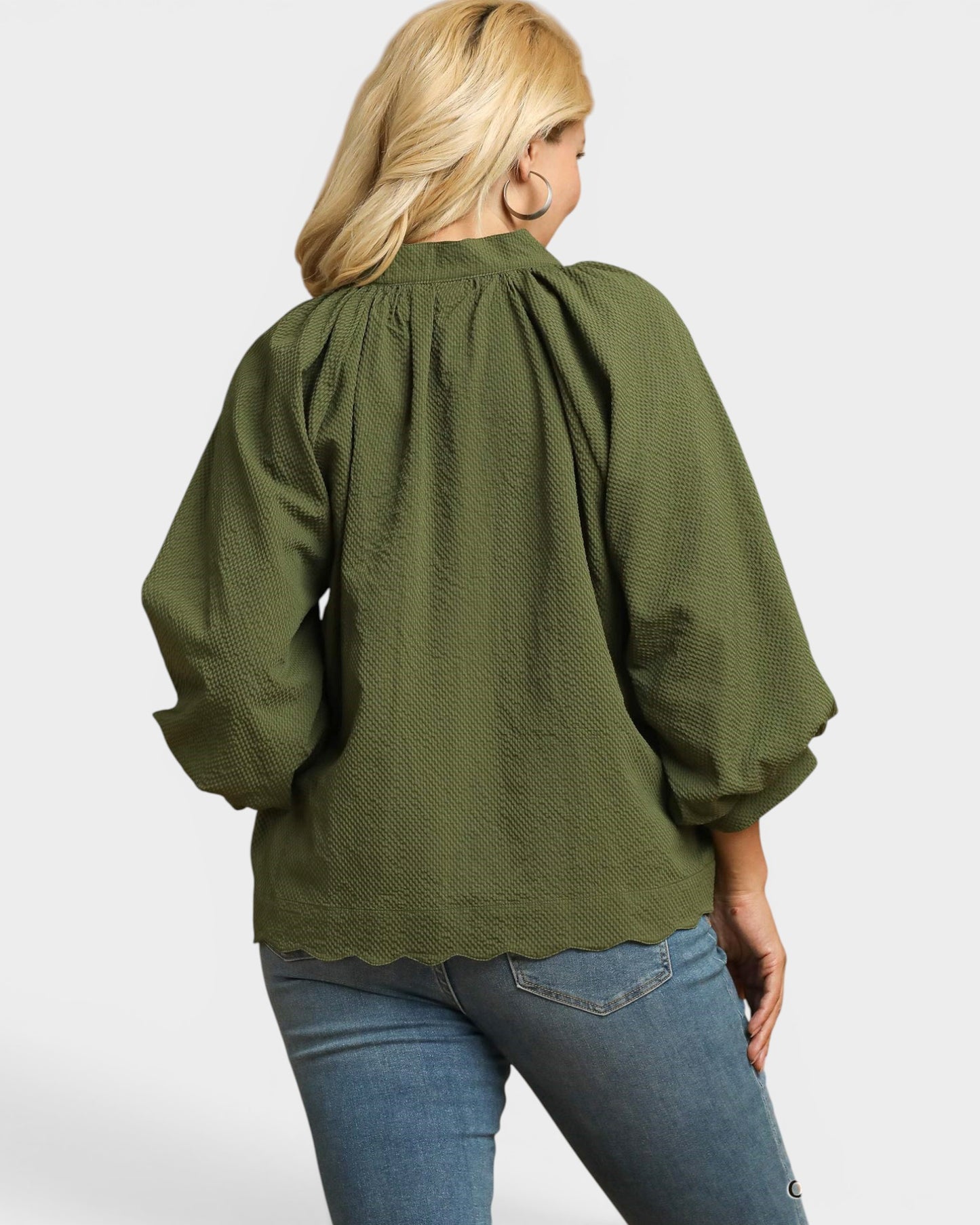 Person wearing a green blouse with puffed sleeves on a white background