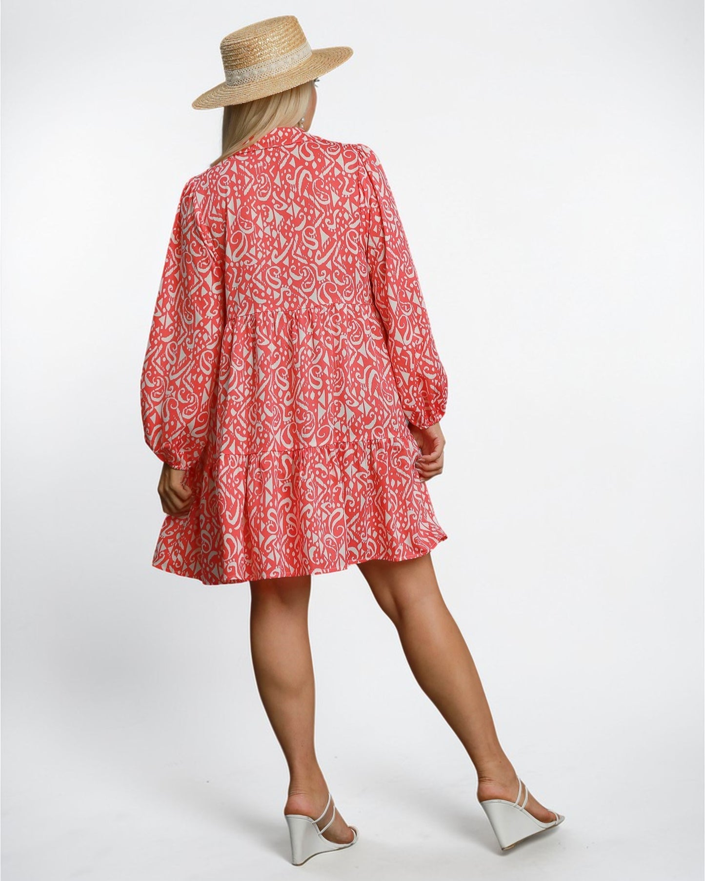 Person wearing a red patterned dress and straw hat on a white background