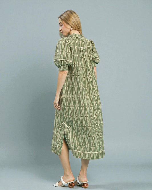 Woman wearing a green patterned dress on a gray background