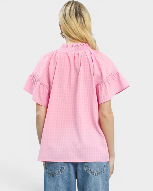 Person wearing a pink blouse with smocked details on a white background