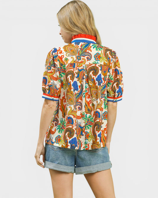 Person wearing a colorful patterned shirt and denim shorts on a white background