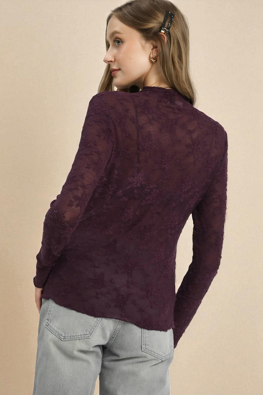 Woman wearing a purple sweater and light gray pants against a beige background