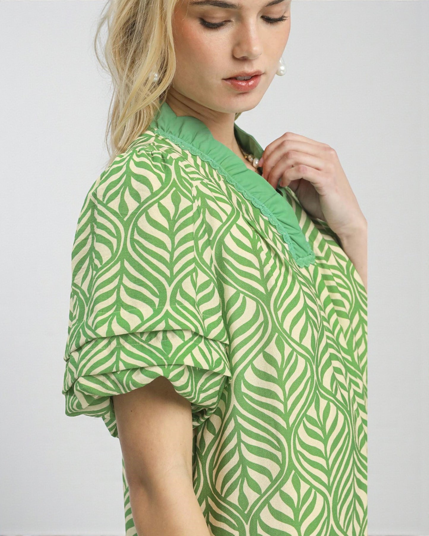 Woman wearing a green and white patterned dress against a plain background