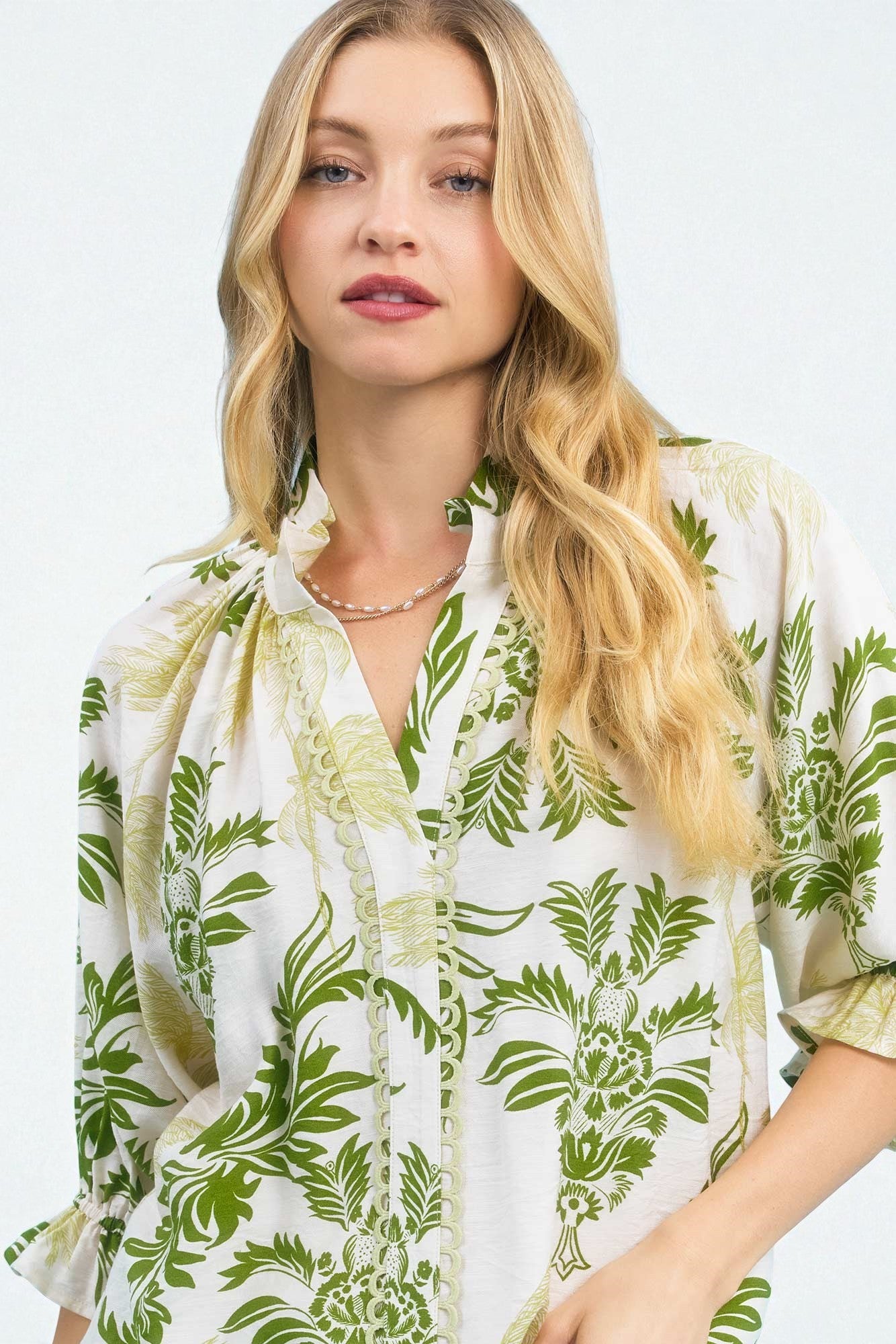 Woman wearing a white blouse with green leaf pattern on a light gray background