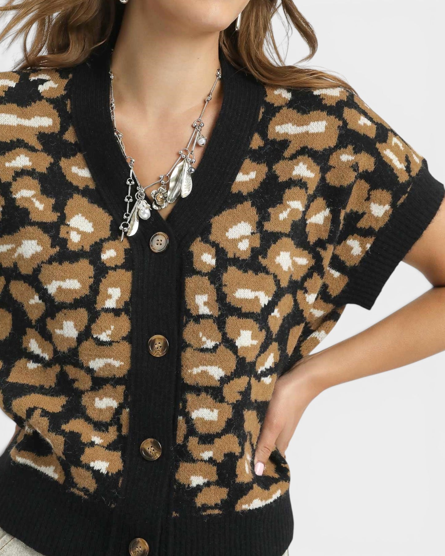 Person wearing a leopard print cardigan with a neutral background