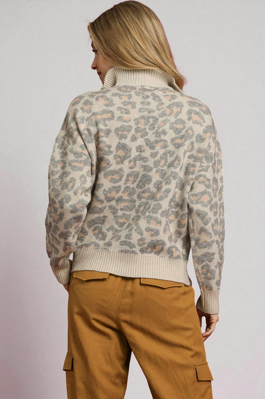 Person wearing a leopard print sweater and brown pants on a plain background