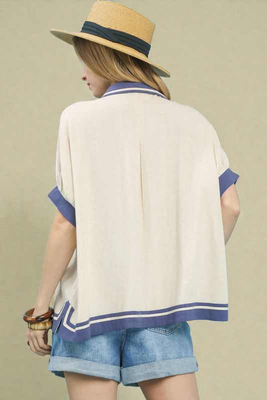 Person wearing a beige cardigan with blue trim, denim shorts, and a straw hat on a beige background