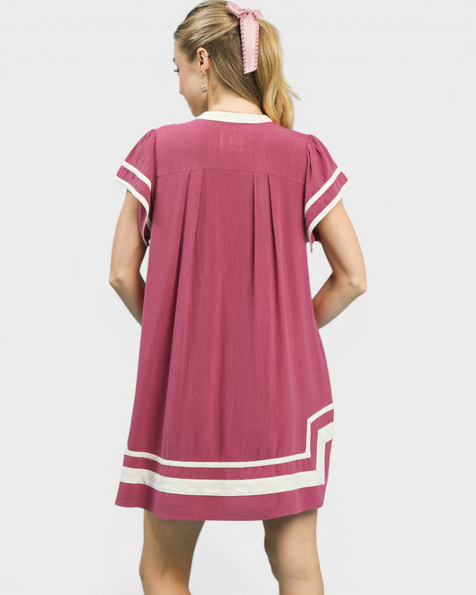 Woman wearing a pink dress with white trim on a white background