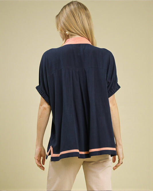 Woman wearing a navy blue top with pink trim on a beige background