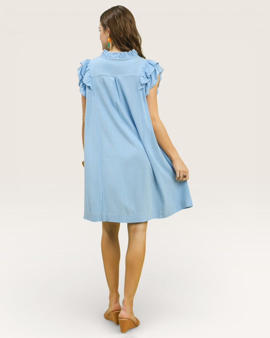 Woman wearing a light blue dress with ruffled sleeves on a white background