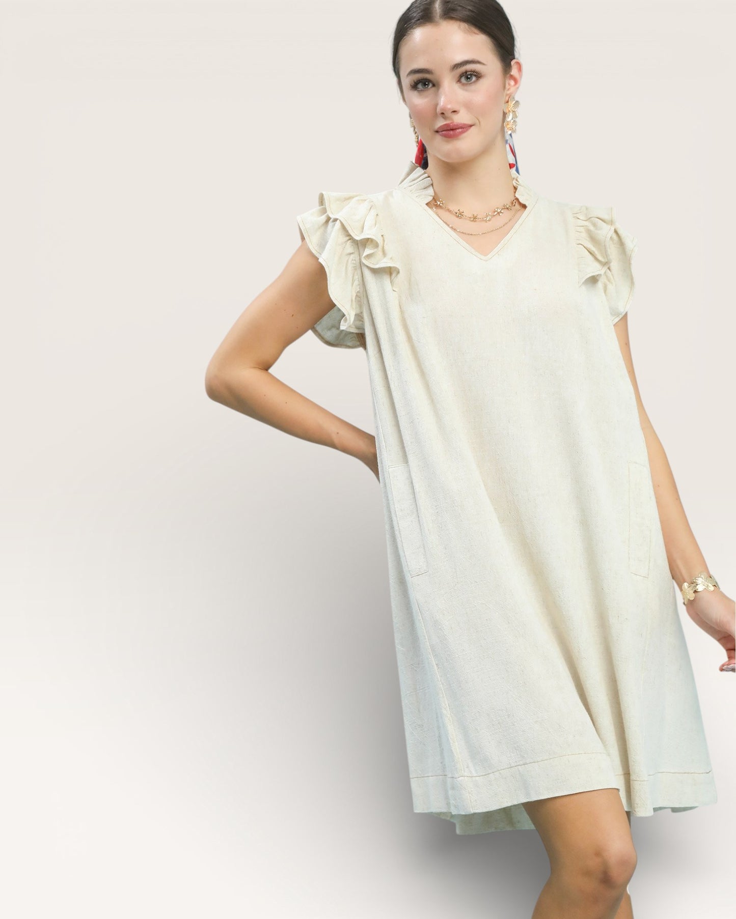 Woman wearing a white dress with ruffled sleeves on a light gray background