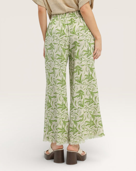 Person wearing green leaf-patterned pants on a white background