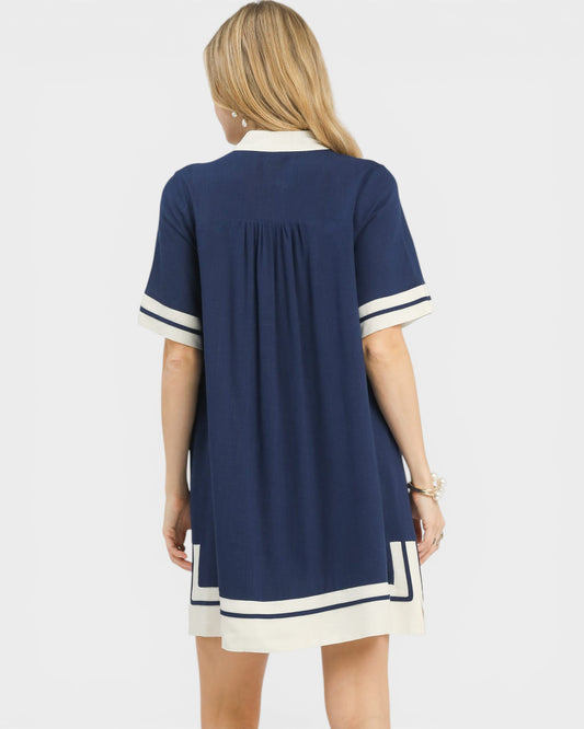 Woman wearing a navy dress with white accents on a white background