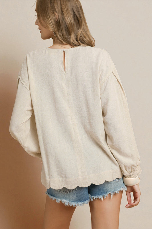 Woman wearing a beige blouse and denim shorts against a beige background