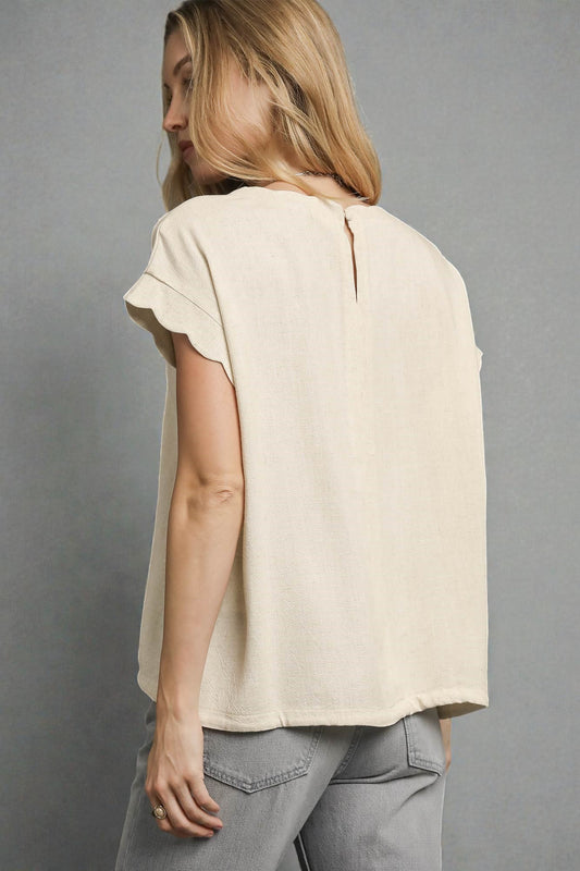 Woman wearing a beige t-shirt and gray pants against a gray background