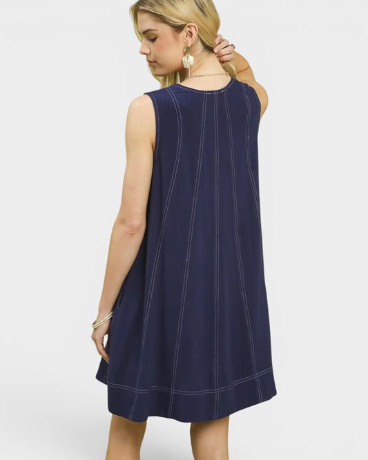 Woman wearing a navy blue dress with white stitching on a white background