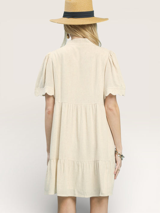 Woman wearing a beige dress and straw hat on a plain background