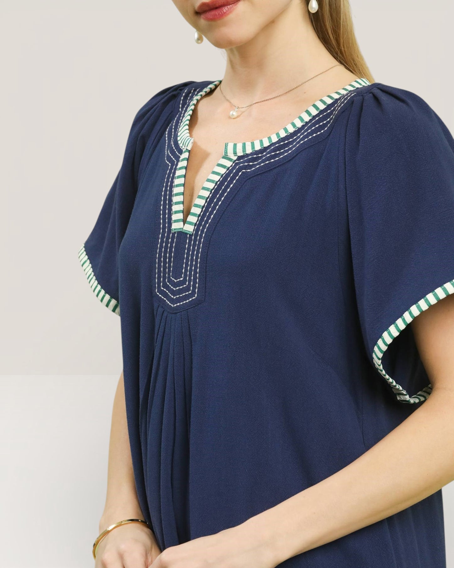 Navy blue dress with green trim on a plain background