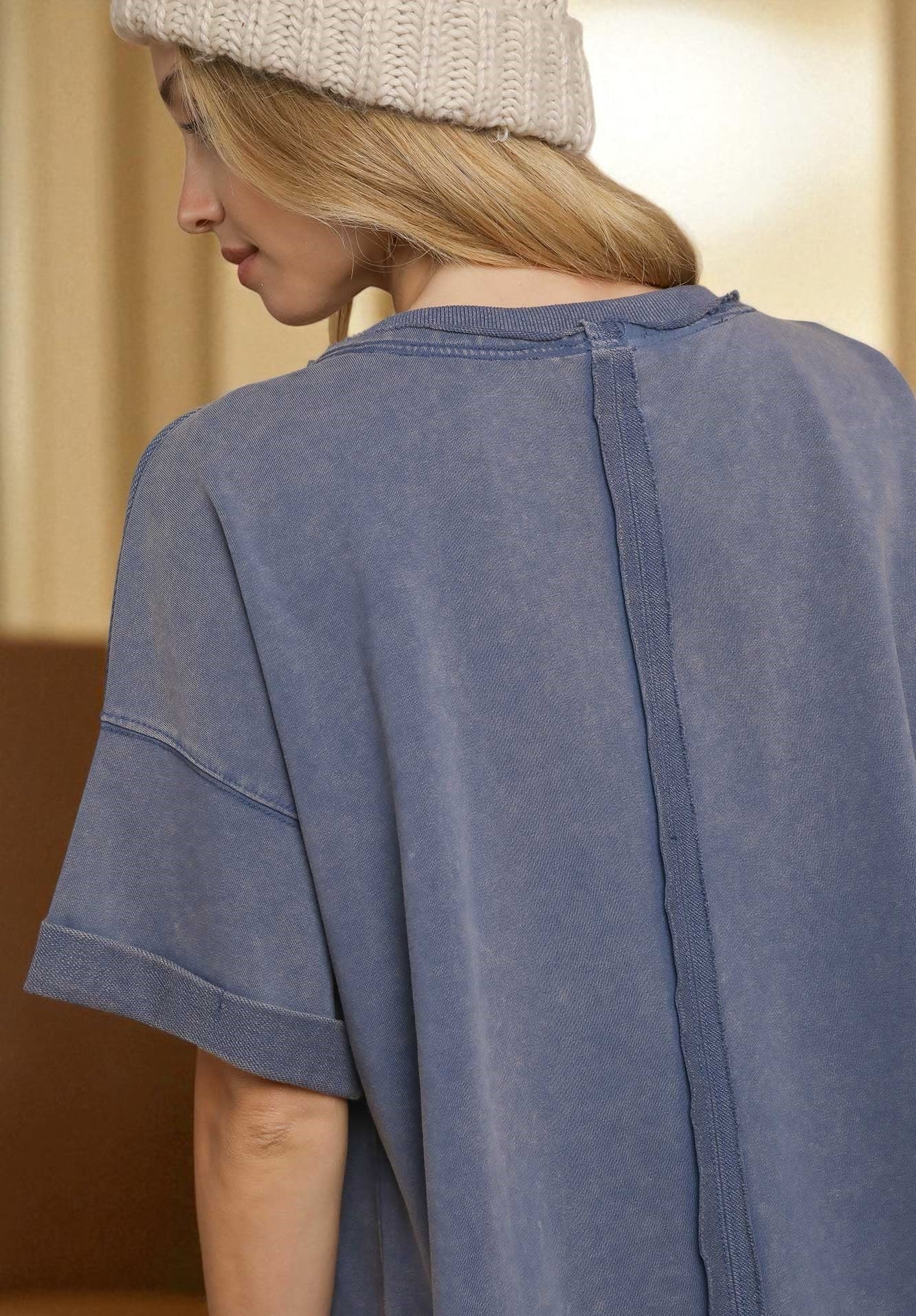 Person wearing a denim blue shirt with a neutral background