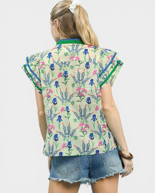 Woman wearing a colorful floral-patterned shirt with denim shorts on a white background