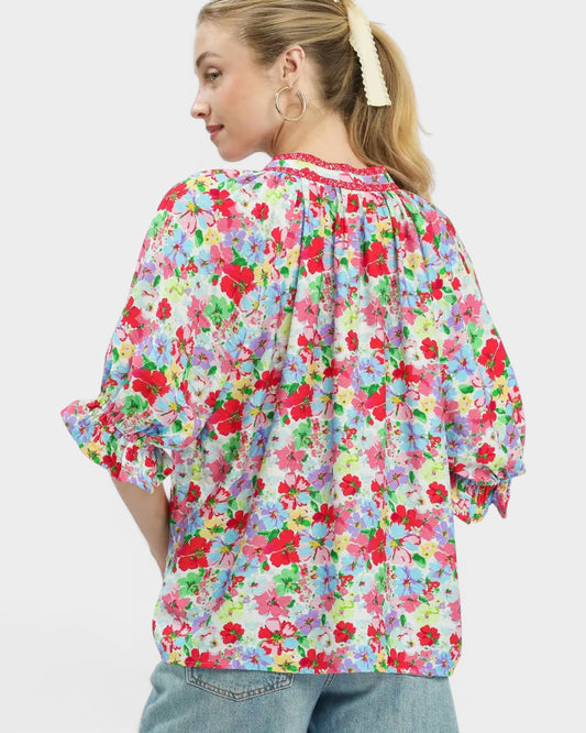 Woman wearing a colorful floral blouse on a white background