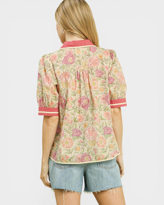 Woman wearing a floral blouse with pink accents on a white background
