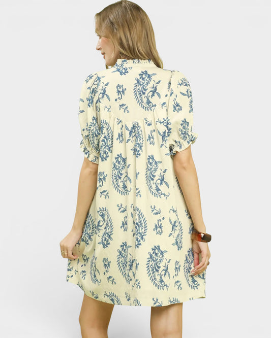 Woman wearing a yellow dress with blue floral pattern on a white background